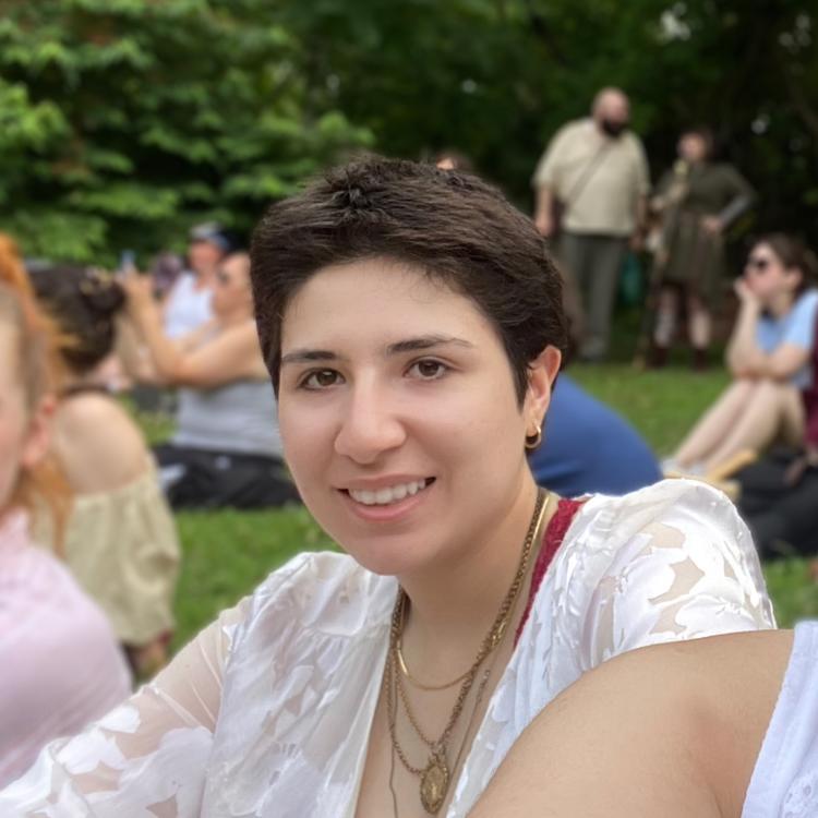 One of the research Assistants Selinay, sitting on a lawn with people in the background